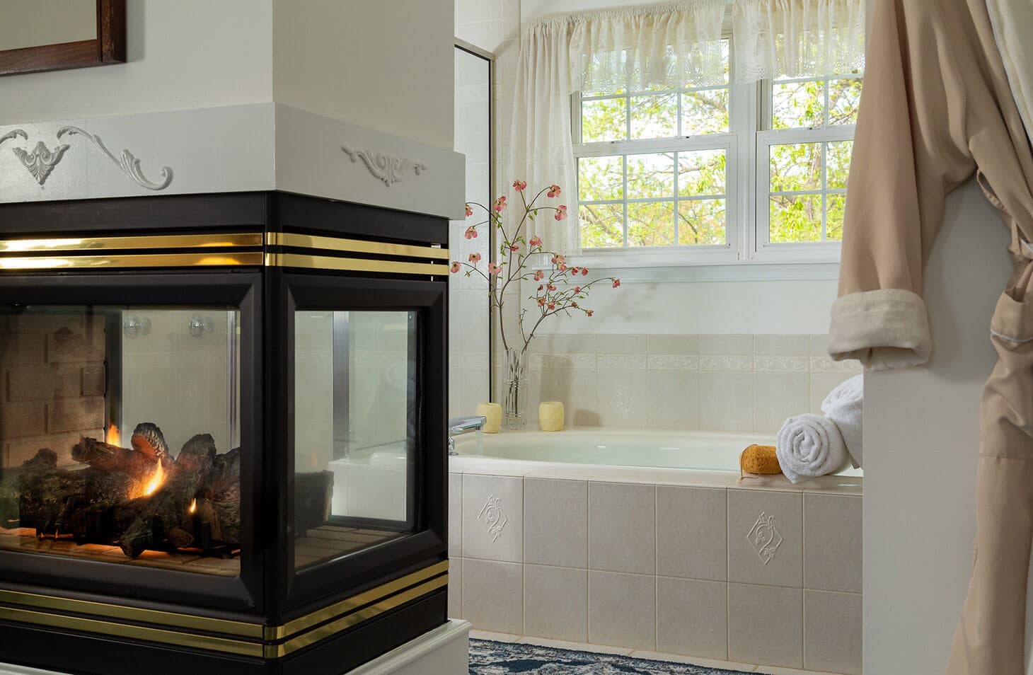 A cozy bathroom featuring a fireplace, a soaking tub, and natural light from multiple windows.